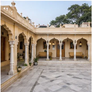 Peaceful Indian spiritual-stay courtyard with traditional arches and simple guest accommodation